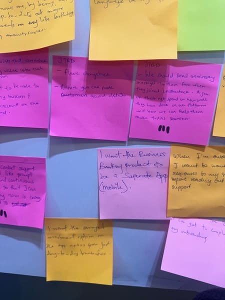 Close-up of research sticky notes covered in handwritten jobs-to-be-done statements